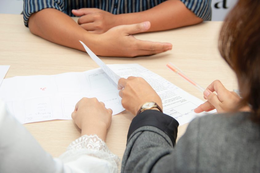 Three people discuss some hand-drawn wireframes in what seems like it could be an interview setting.