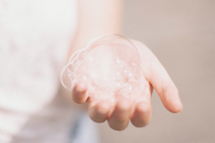 A white person's hand holding a mound of soap bubbles.